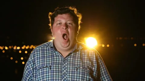 Bored man standing and yawning at night outdoor, portrait Видео 101397595