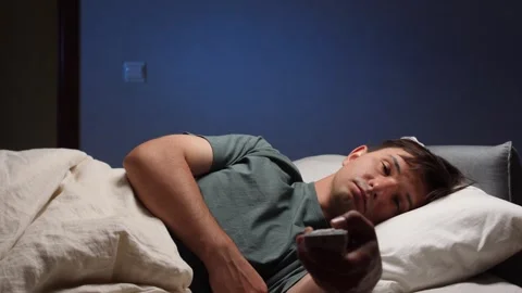 Bored man watching television in bed at night 库存影片 316753993