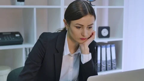 Bored office worker at desk staring at computer screen with hand on chin Stock Footage 71114448