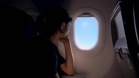 Bored passenger sitting by airplane window looking outside during flight travel Vídeo Stock 342334243