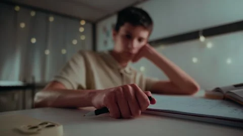 Bored Student Tapping Pen on Desk While Doing Homework at Night Stock Footage 336388656
