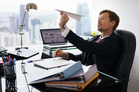 Bored White Collar Worker Throwing Paper Airplane In Office Stock Photos