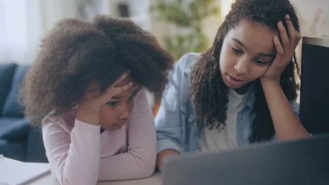Bored young afro-american sisters watching online lesson on laptop, education Stock Footage