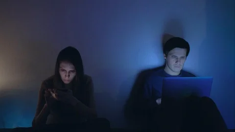 Bored young couple using smartphone and laptop at night Stock Footage 120168491