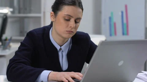 Bored young woman typing laptop sitting table, office work routine, tiredness Stock Footage