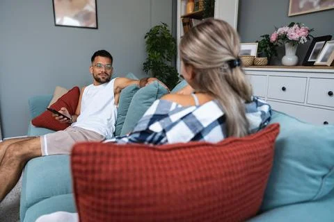Boredom Concept. Young couple using smartphones, sitting on couch at home, .. Stock Photos