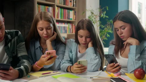 Boring addict four teens pupils classmates students using smartphones apps Stock Footage 306579833