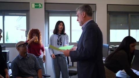 The boss distributes task folders to employees in a modern office setting. Vídeo Stock 276082077