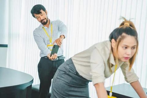 Boss or supervisor is secretly using a mobile phone to film the buttocks of.. Foto stock