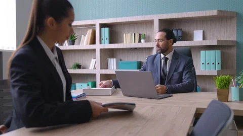 A boss is sitting at a desk, a worker has arrived, discussing work issues Stock Footage 233994344