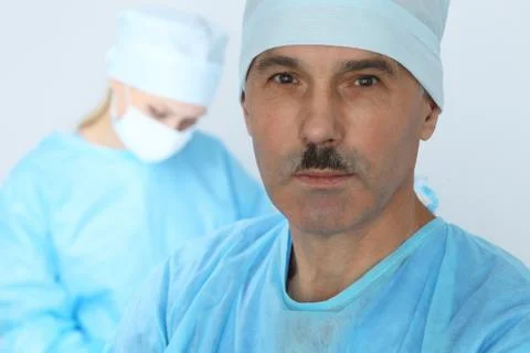 Boss surgeon is examining the operation while medical team are busy of patient Фото