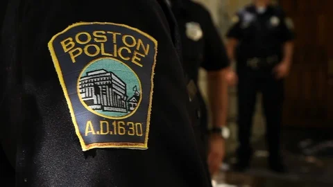 Boston cop's police patch, waiting around at crime scene with other cops Stock Footage 92186442