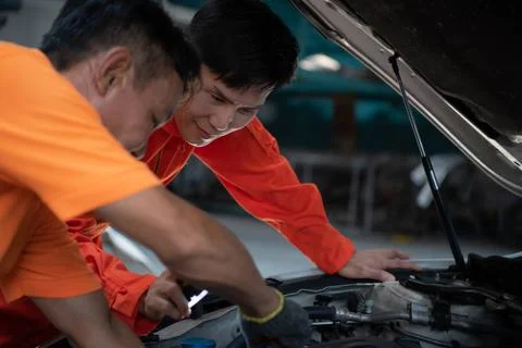 Both of auto mechanics are inspecting the engine of a customer s car being... Foto stock