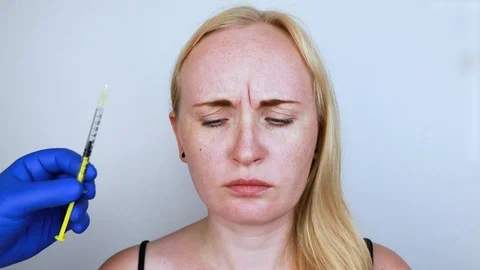 Botox injection in the forehead, remove the vertical wrinkle. Young woman on rec Stock Footage 112888214