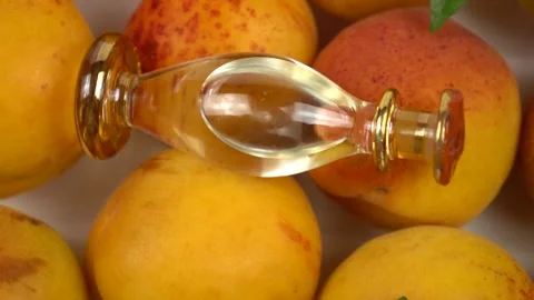 Bottle with apricot kernel oil placed on the fresh apricot fruit,  slow motion Stock Footage 278038526