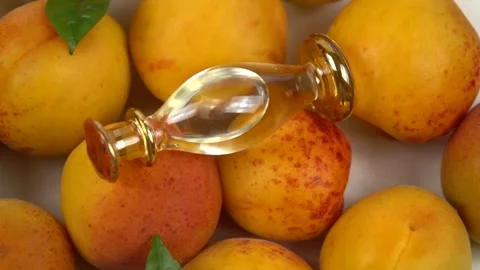 Bottle with apricot kernel oil placed on the fresh apricot fruit,  slow motion Stock Footage 278038534