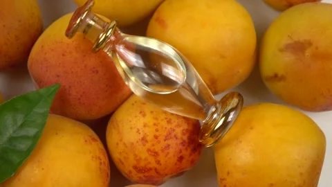 Bottle with apricot kernel oil placed on the fresh apricot fruit,  slow motion Stock Footage 278038538