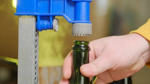 A bottle of beer is capped with a hand-held device against a background of Stock Footage 185896228