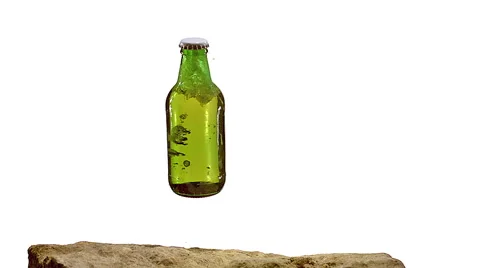 Bottle of Beer falling and Splashing on Stone against White Background, Slow Stock Footage