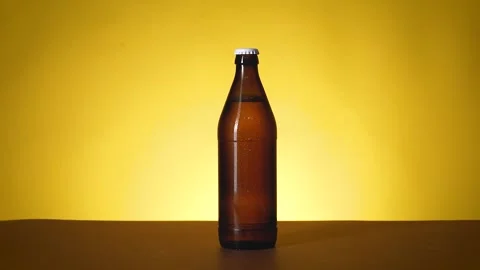 A bottle of beer is on the table, a drop of moisture drips on it. Stock Footage 196887435