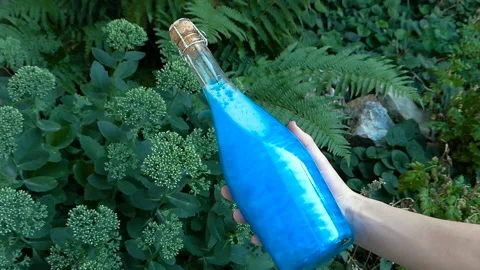 Bottle blue Elixir in hand Stock Footage 93902321