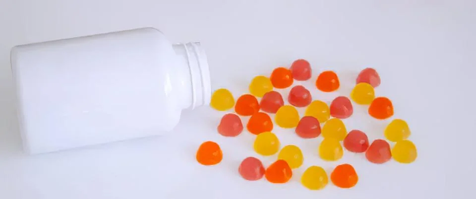 Bottle of candy drops spilling on white surface Stock Photos