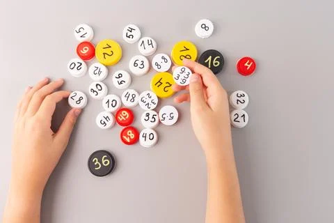 Bottle cap with math problems in child's hand, scattered numbered caps on g.. Stock Photos