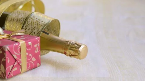 The bottle of champagne with gold glossy ribbon and red gift Stock Photos