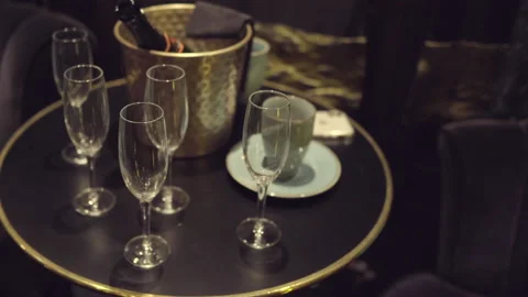 Bottle of champagne in an ice bucket on a table with five champagne flutes Stock Footage 130567754