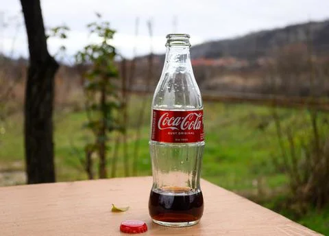 A bottle of Coke left on the table. Stock Photos
