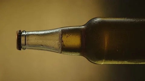 A bottle of cold beer slowly rotates against a dark background, close-up Stock Footage 157548376