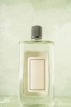 Bottle of cologne with empty label over green Foto stock