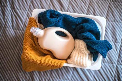 Bottle of detergent with sweaters in container. Stock-Fotos