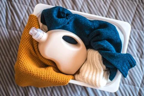 Bottle of detergent with sweaters in container. Stock Photos