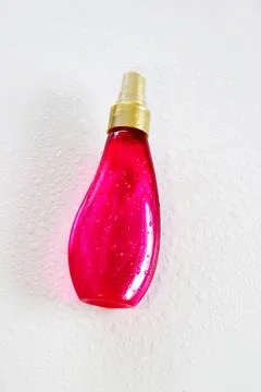 Bottle of essence perfume on a light background with sunlight and water drops Stock Photos