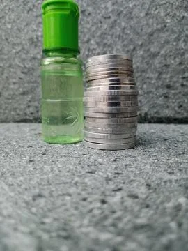 Bottle Filled with Liquid Beside Stack of Coins – Symbolic Contrast Stock Photos