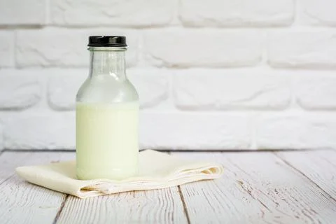 Bottle of fresh milk on white table cloth with wall in kitchen with copy sp.. Stock Photos