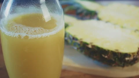 Bottle of freshly pressed pineapple juice with a pineapple sliced in half in the Stock Footage 273510596