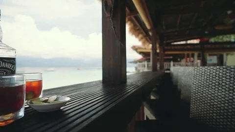 Bottle of Jack Daniels and 2 glasses in beachfront bar - illustrative, editorial Stock Footage 77954254