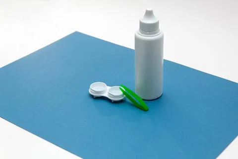 Bottle with lens solution, case and green tweezers on the table. Foto stock