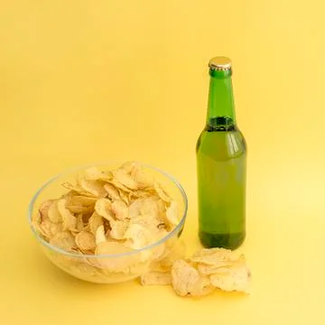 Bottle of light beer and chips on a yellow background Stock Photos