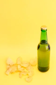 Bottle of light beer and chips on a yellow background Stock Photos