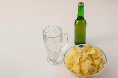 Bottle of light beer, empty beer glass mug and potato chips on white table Stock Photos