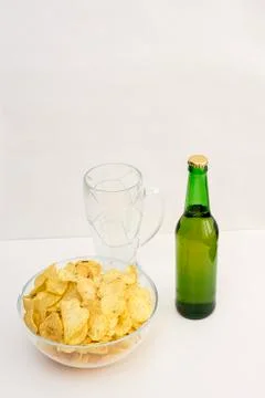 Bottle of light beer, empty beer glass mug and potato chips on white table Stock Photos