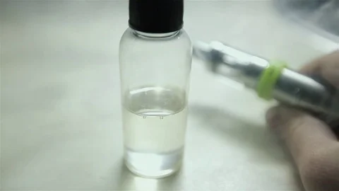 Bottle with liquid and flavor for electonic cigarette stay on the table. Stock Footage 72414904