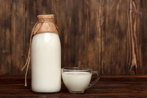Bottle of milk and cup on rustic wooden table Stock Photos