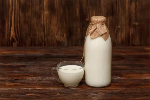 Bottle of milk and cup on rustic wooden table Stock Photos