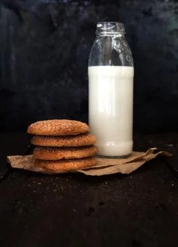 Bottle with milk and a stack of cookies on a dark background, retro style, .. Stock Photos