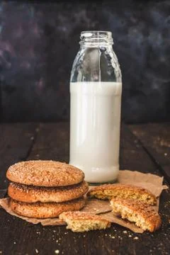 Bottle with milk and a stack of cookies on a dark background, retro style, vi Stock Photos