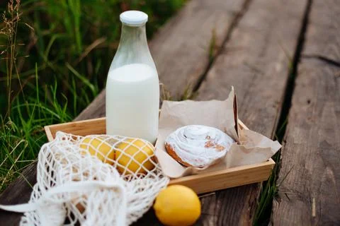 A bottle of milk and a string bag with fruit on wooden boards on the lake Foto stock